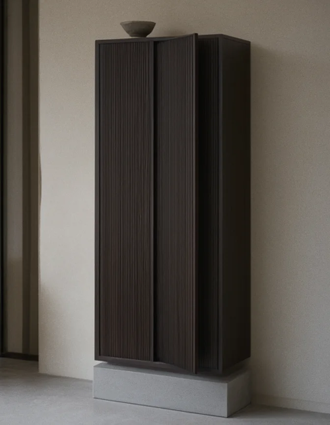 Concept render: a tall narrow cabinet in fumed oak, dark and smoky with the grain showing, its two doors faced in fine vertical reeding with no handles, one door ajar, standing on a low plinth of smooth cast concrete against a limewashed wall.
